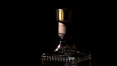 Textured glass bottle with a gold cap, shown against a black background.