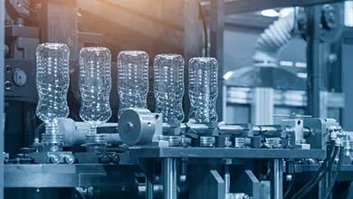 Close-up of clear, textured plastic bottles moving along an industrial production line.