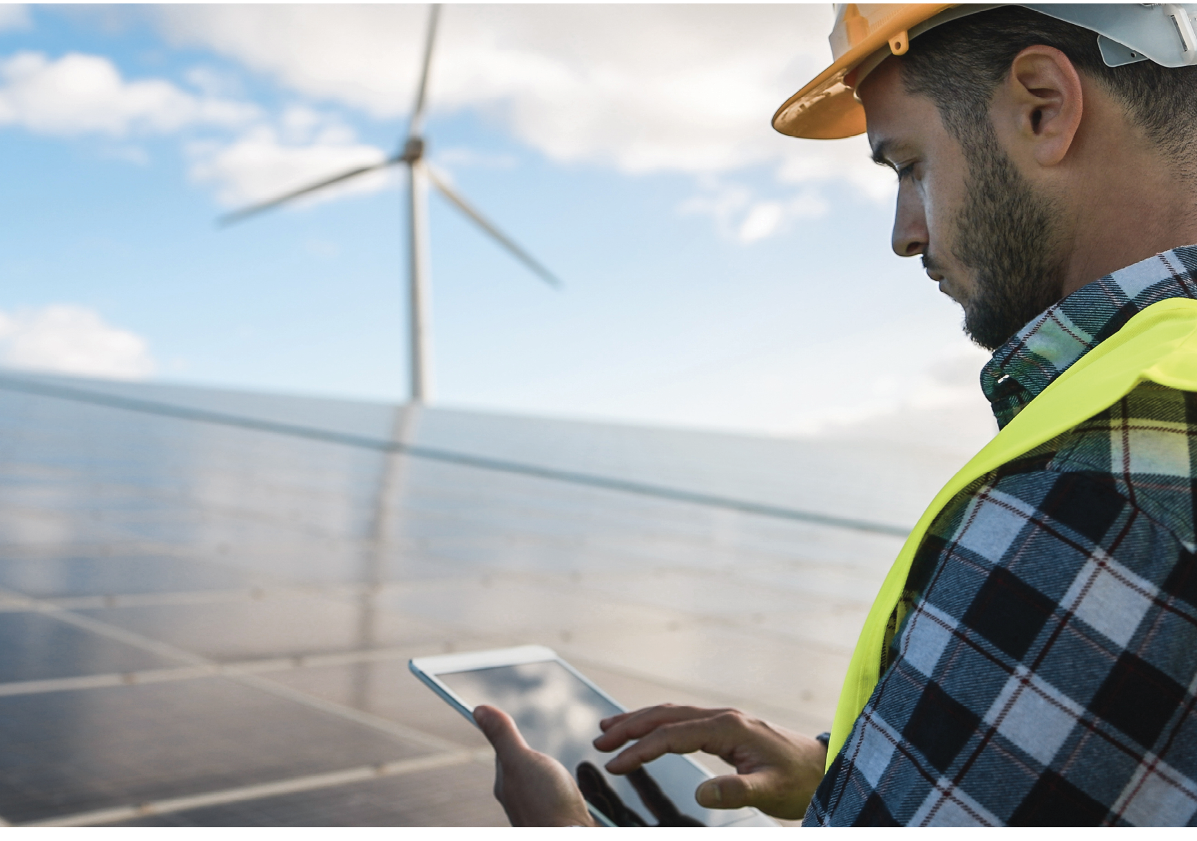 Young man working with digital tablet at renewable energy farm - Eco and technology concept - Focus on ear
